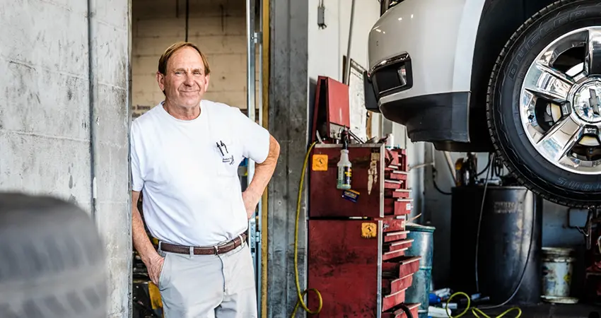 smiling man in front of tire service shop